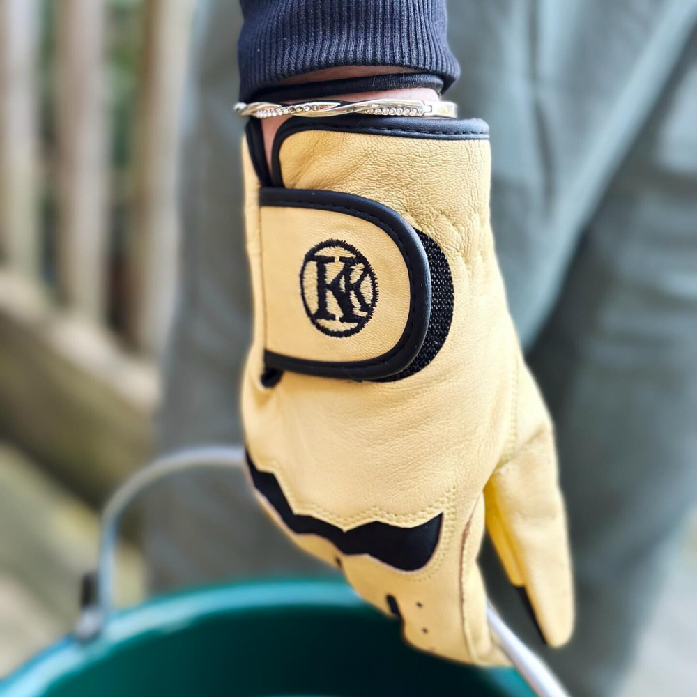 Closeup image of a person wearing a Kunkle barn glove and holding a bucket.